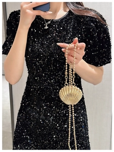 Detailed view of a gold shell-shaped evening bag with a matching beaded metal chain