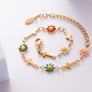Bracelet en acier doré avec fleurs de marguerites colorées et croix sur fond blanc