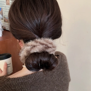 Dettaglio dell'elastico per capelli in peluche tortora scuro acconciato su uno chignon