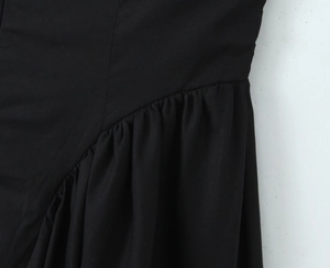 Detailed view of the black deep V-neck dress featuring elegant pleated waist stitching