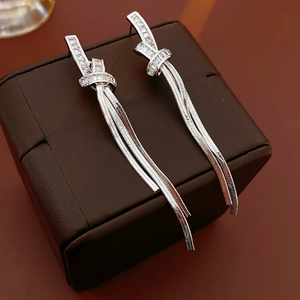 Detail of silver knot earrings with zircon stones and long tassel snake chains