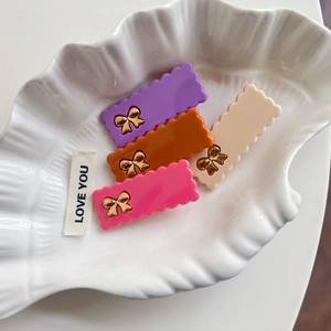 Lot de quatre barrettes rectangulaires ondulées avec nœuds dorés en violet, rose et beige