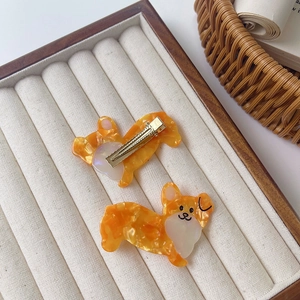 Detailed view of two cute Corgi hair clips made of orange and white marble acetate