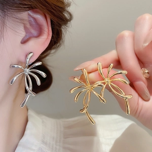 Detailed view of large gold and silver flower stud earrings with shimmering rhinestones