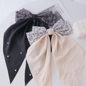 Detail of vintage floral bow hair clips with white pearls and long ribbon tails