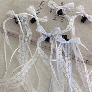 Detail of white lace bow hair clips with long ribbons on a minimalist linen background