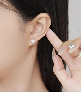 Close-up of a classic claw-set round diamond stud earring worn on a female earlobe