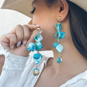 Close-up of bohemian turquoise shell earrings with golden scallop pendant on model