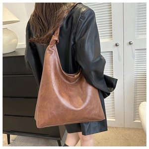 Detail of caramel brown large tote bag with chic knot handle design on shoulder strap