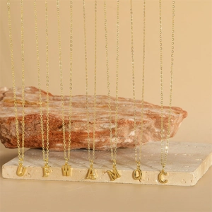 Detailed close-up of multiple gold initial letter pendants on fine link chains