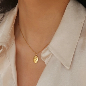 Detail of a gold titanium steel necklace with an irregular oval rose flower pendant