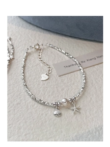 Close-up of S925 silver bracelet featuring irregular beads, a pearl, and starfish charms