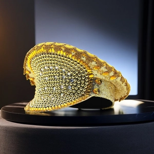 Macro detail of the golden bridal captain hat featuring sequins and sparkling gemstones