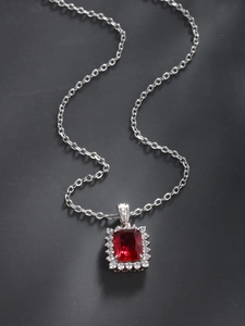 Close-up of elegant silver necklace with red rectangular gemstone and zircon halo