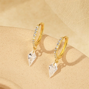 Macro shot of gold silver earrings with sparkling crystals and kite-shaped drop pendants