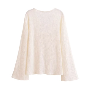Detail view of cream long sleeve top with textured pleats and tie-front closure