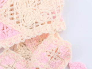 Detailed close-up of pink and cream crochet knit fabric with hollow floral pattern