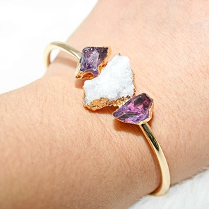 Macro shot of gold plated bracelet featuring amethyst and white crystal cluster stones