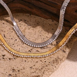 Close-up of gold and silver herringbone necklaces with micro-set zircon on textured rock