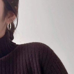 Close-up detail of a model wearing minimalist silver hoop earrings with a polished finish