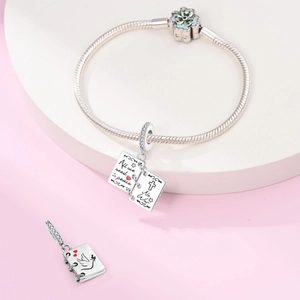 Detail of silver snake chain bracelet featuring an openable book charm with peace engraving