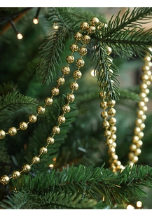 Close-up of shiny golden bead chain garland wrapped around a green Christmas tree