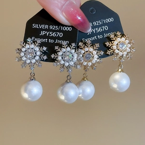 Detailed macro shot of 925 silver snowflake earrings with pearls and zircon in gold and silver