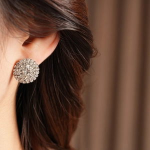Gros plan d'un mannequin portant une boucle d'oreille ronde en argent sertie de cristaux