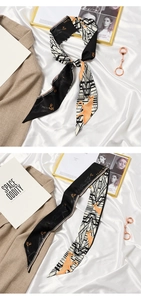 Detail of French ribbon scarf with beige and black geometric patterns and gold horse prints
