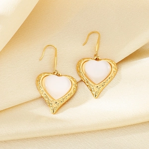 Detail of gold heart earrings with cat eye stones on elegant golden silk fabric