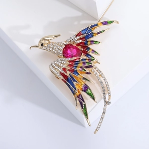 Detail of golden phoenix brooch with colorful enamel, rhinestones and magenta gemstone