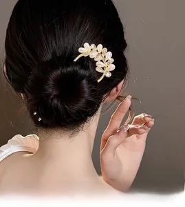 Détail d'épingle à cheveux dorée en U avec perles et glands sur une coiffure élégante