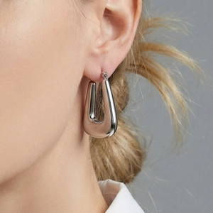 Polished silver U-shaped hoop earrings in geometric design worn for a minimalist chic style