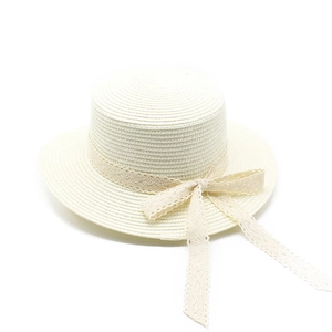 Detailed close-up of cream flat top straw hat with elegant lace ribbon and bow decoration