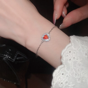 Close-up of red heart-shaped gemstone bracelet with sparkling zircon halo and silver chain