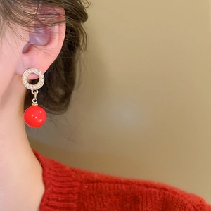 Detail of elegant gold hoop earrings with sparkling crystals and red pearl drops on model