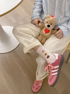 Détail de chaussettes roses à rayures avec motif chien, pantalon velours et baskets