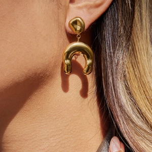 Boucles d'oreilles fer à cheval dorées avec texture métal martelé sur un mannequin