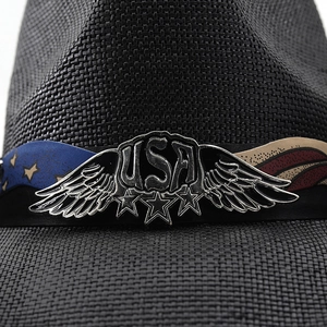 Macro detail of black straw cowboy hat with USA metal badge and American flag band