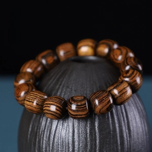 Macro shot of tiger skin sandalwood beads with natural wood grain on a ceramic jar