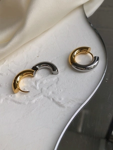 Close-up of two-tone gold and silver chunky hoop earrings with a hinged closure
