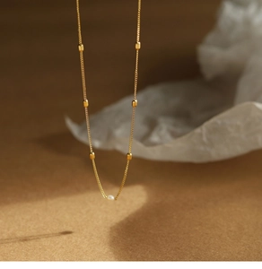 Detailed close-up of 18K gold-plated necklace with elegant pearls and metal beads