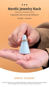 Close-up of a light blue ceramic cone jewelry display stand holding a ring on orange background