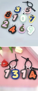 Detail of colorful number-shaped leather keychains with stitching and metal clasp