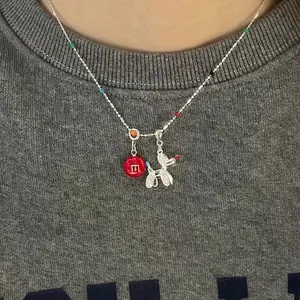 Collier de perles colorées avec pendentif chien ballon argenté sur un sweat gris