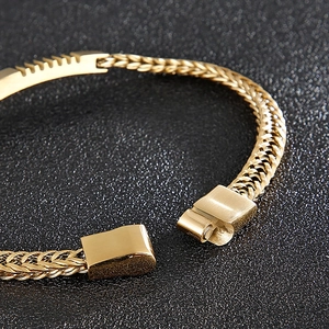 Macro detail of golden stainless steel woven chain bracelet with a magnetic clasp
