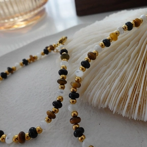 Natural tiger eye beaded necklace with gold accents draped over a white seashell base