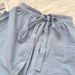 Detail of light blue cotton apron waist with breathable fabric and drawstring ties