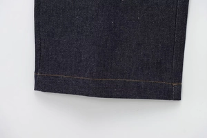 Close-up of dark blue denim hem with contrasting orange double-needle stitching detail