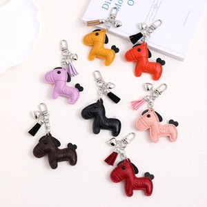 Close-up of colorful faux leather horse charms with tassel and silver hooks for bags